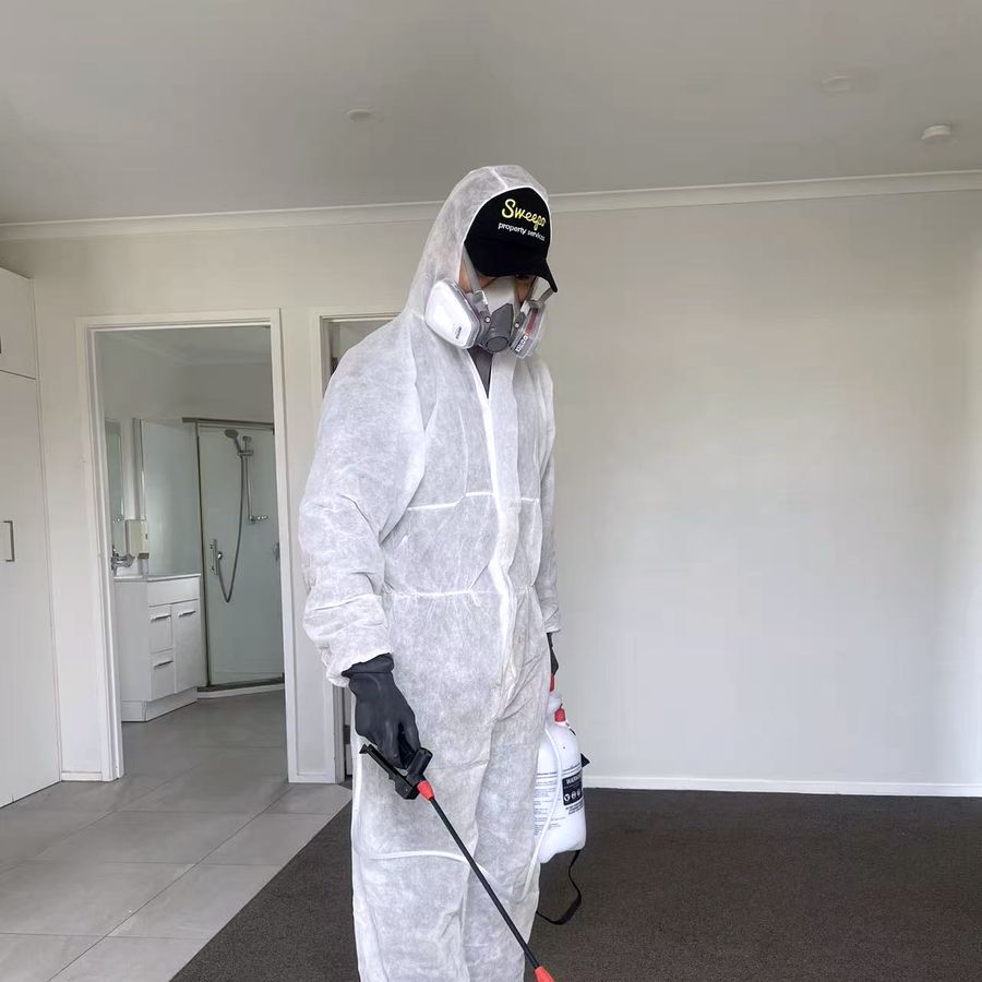 Sweepo technician in full protective equipment treating a carpet